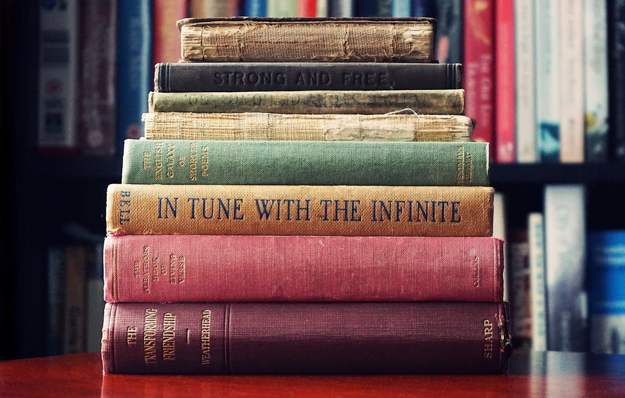 brand-03 A stack of vintage hardcover books on a wooden table in a cozy library setting.