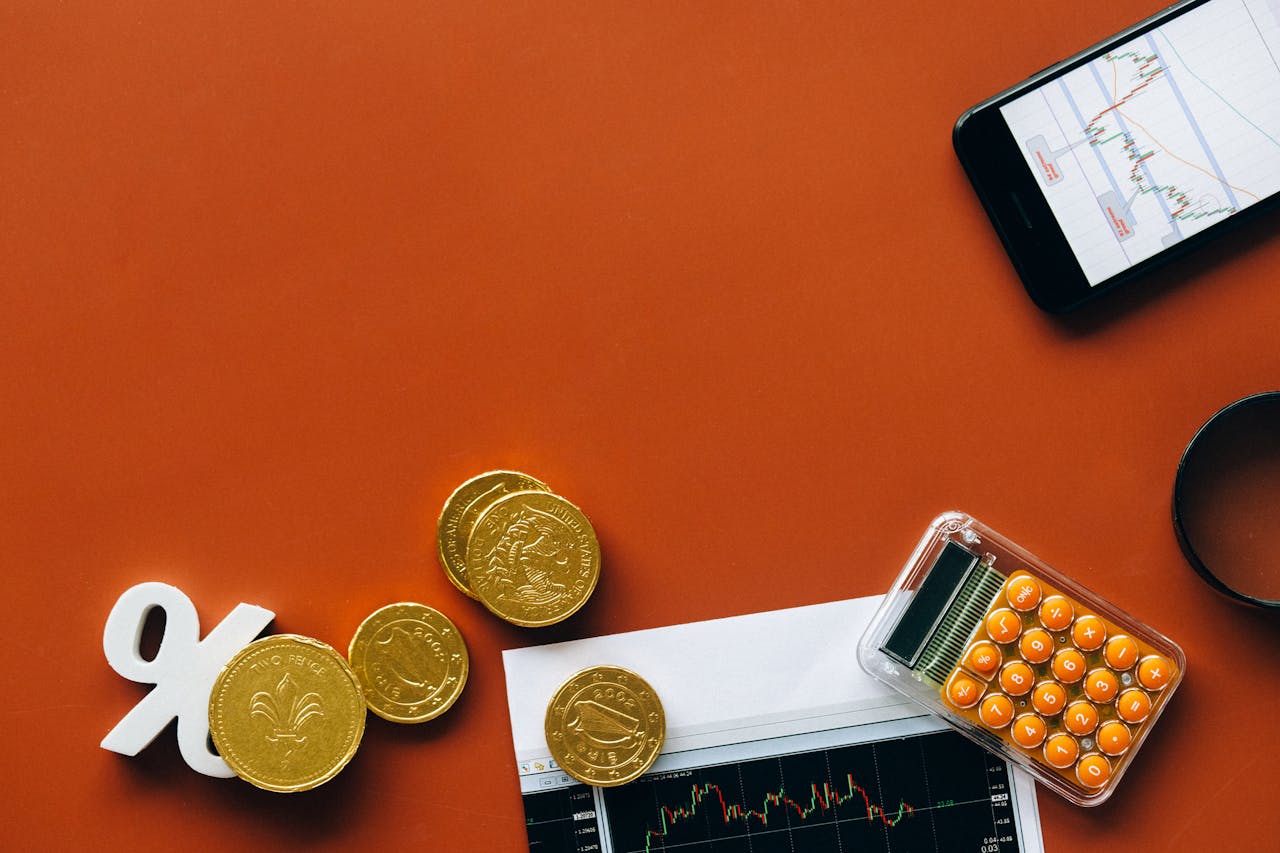 creative-03 Flat lay showing coins, calculator, and charts on a red background for financial analysis and business concepts.